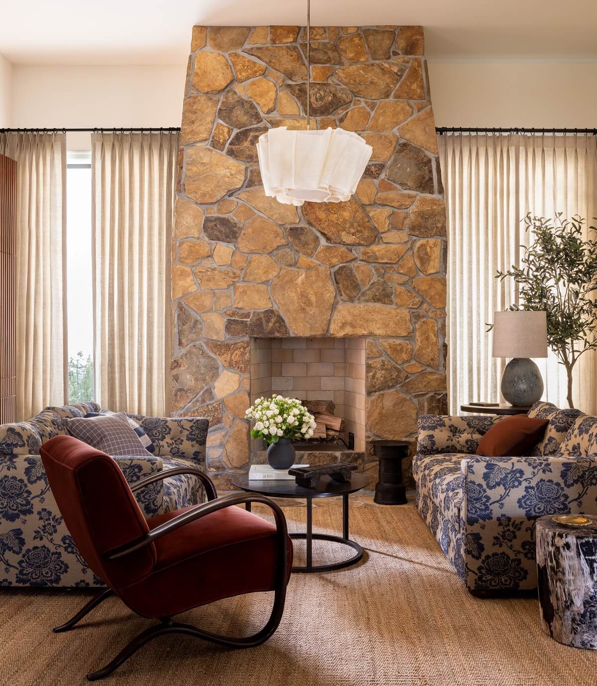 Pink Tones and Black in a Stunning Fox Island Home 11 sitting-room-stone-fireplace-blue-patterned-sofas-red-armchair-nordroom