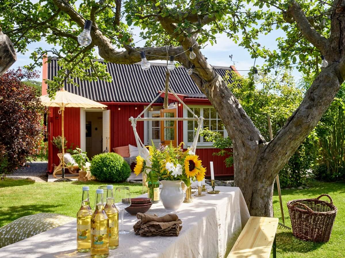 A Cozy Renovated Cottage on a Swedish Allotment 17 garden-tree-dining-table-hanging-chair-nordroom