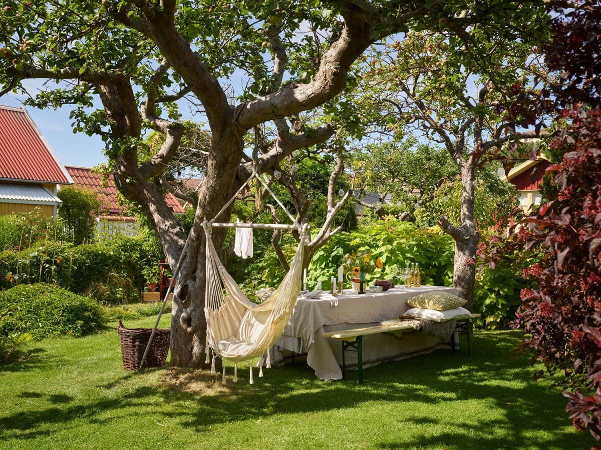 A Cozy Renovated Cottage on a Swedish Allotment 22 swedish-summerhouse-garden-hanging-chair-dining-area-nordroom
