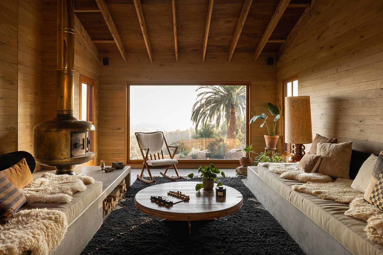 The Warm Mountaintop Home of Actor Hayden Christensen 1 Mountaintop-Home-Altadena-William-Hunter-Collective-Living-room-built-in-sofa-woodburner-panorama-window-nordroom