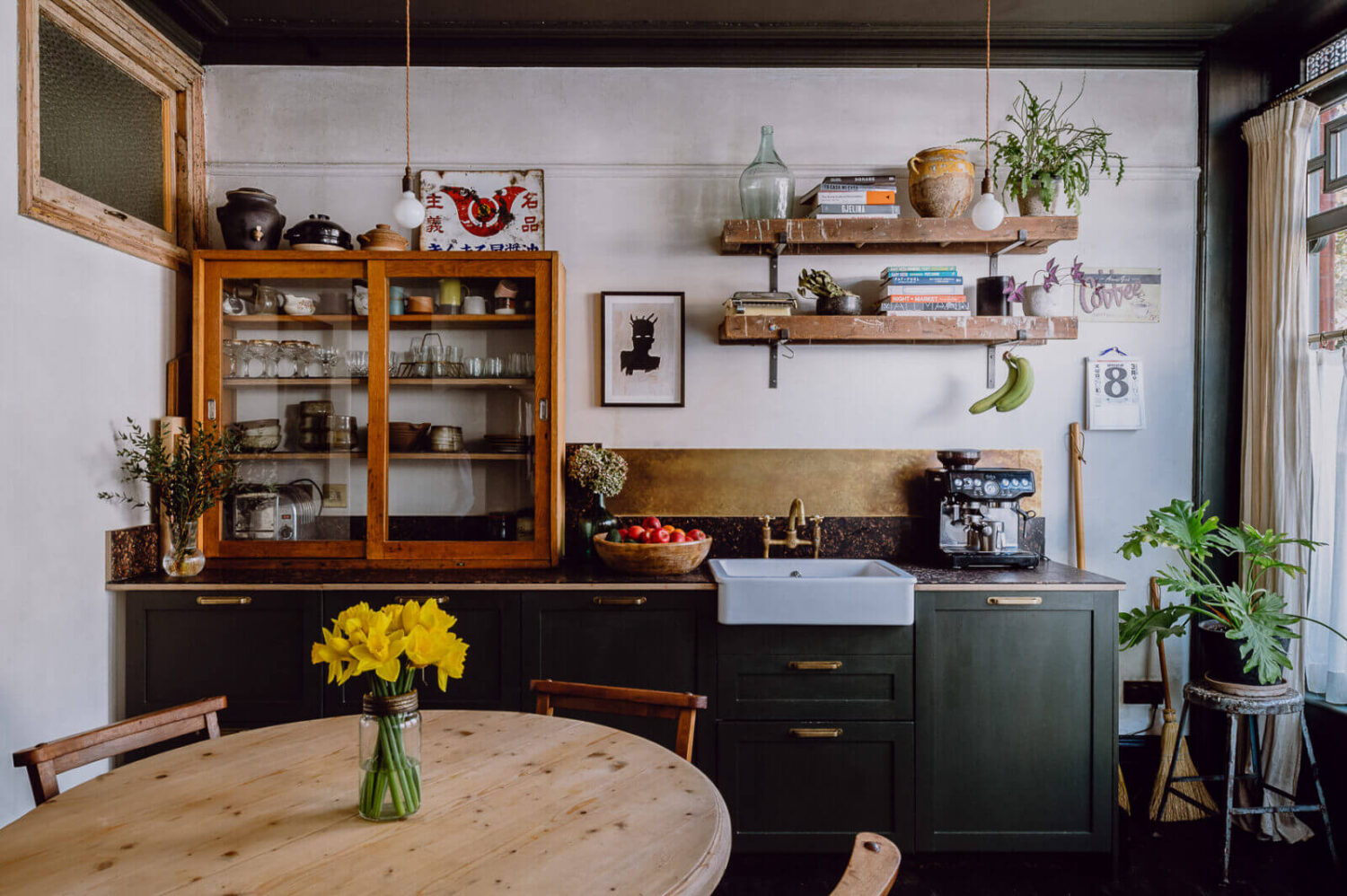A Victorian Watch Shop is Now a Warm Sustainable Home 1 kitchen dark green oak cabinets brass backsplash round kitchen table nordroom