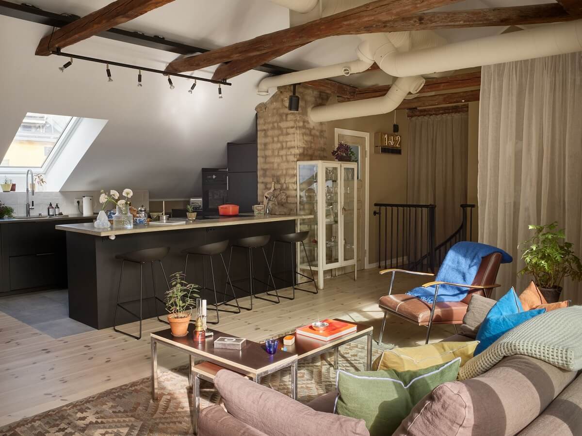 A Scandinavian Penthouse Apartment with Slanted Ceilings 1 open-plan-living-space-penthouse-loft-black-kitchen-exposed-brick-wooden-beams-nordroom