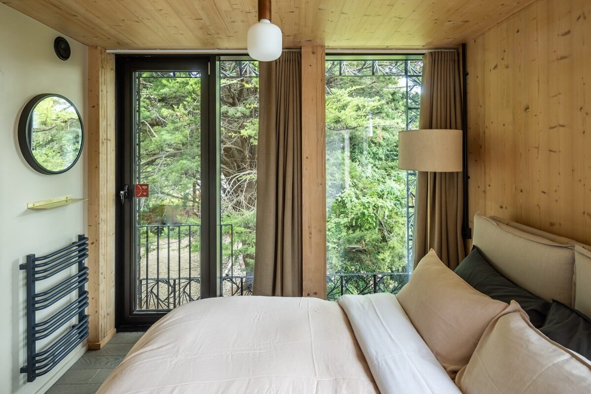 A Modern English Home with a Sculptural Facade 16 bedroom-wooden-walls-balcony-round-mirror-nordroom