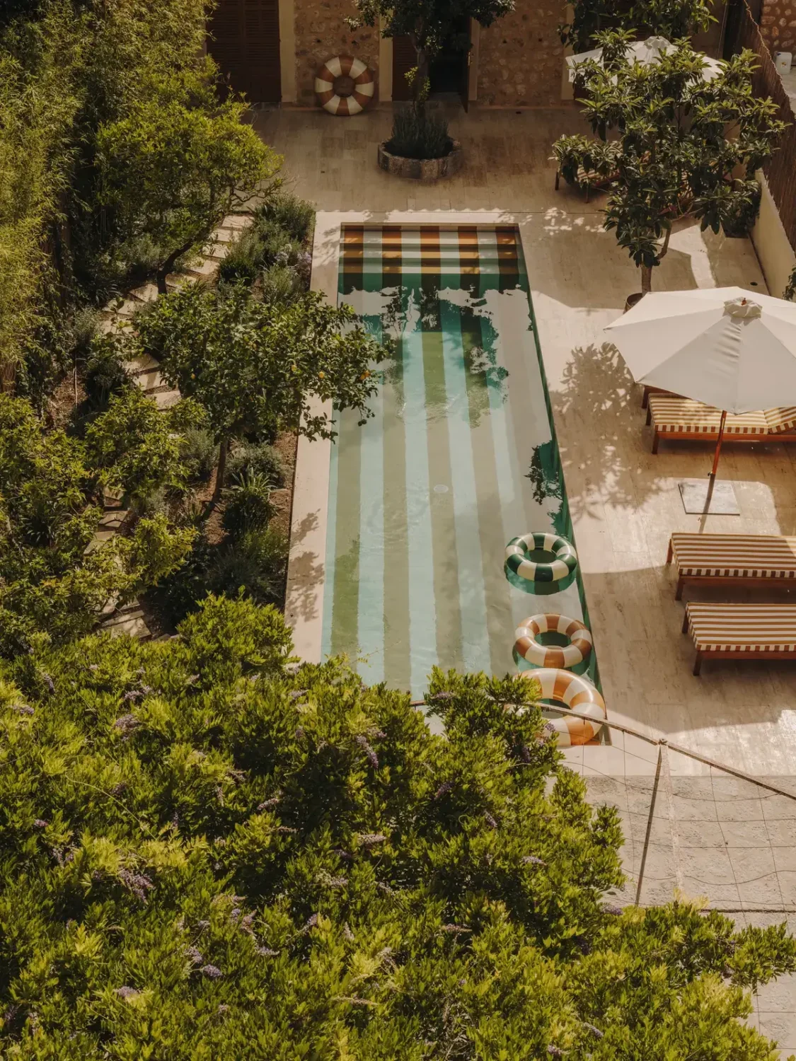 A Historic Townhouse on Majorca with a Striped Pool 31 garden-from-above-with-yellow-white-striped-swimming-pool-nordroom