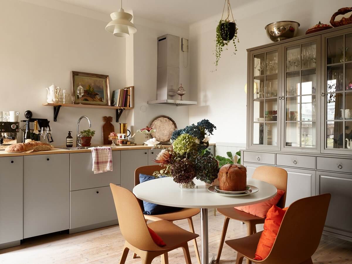 A Charming 1920s Apartment with a Green Bedroom 1 kitchen with gray cabinets and round breakfast table
