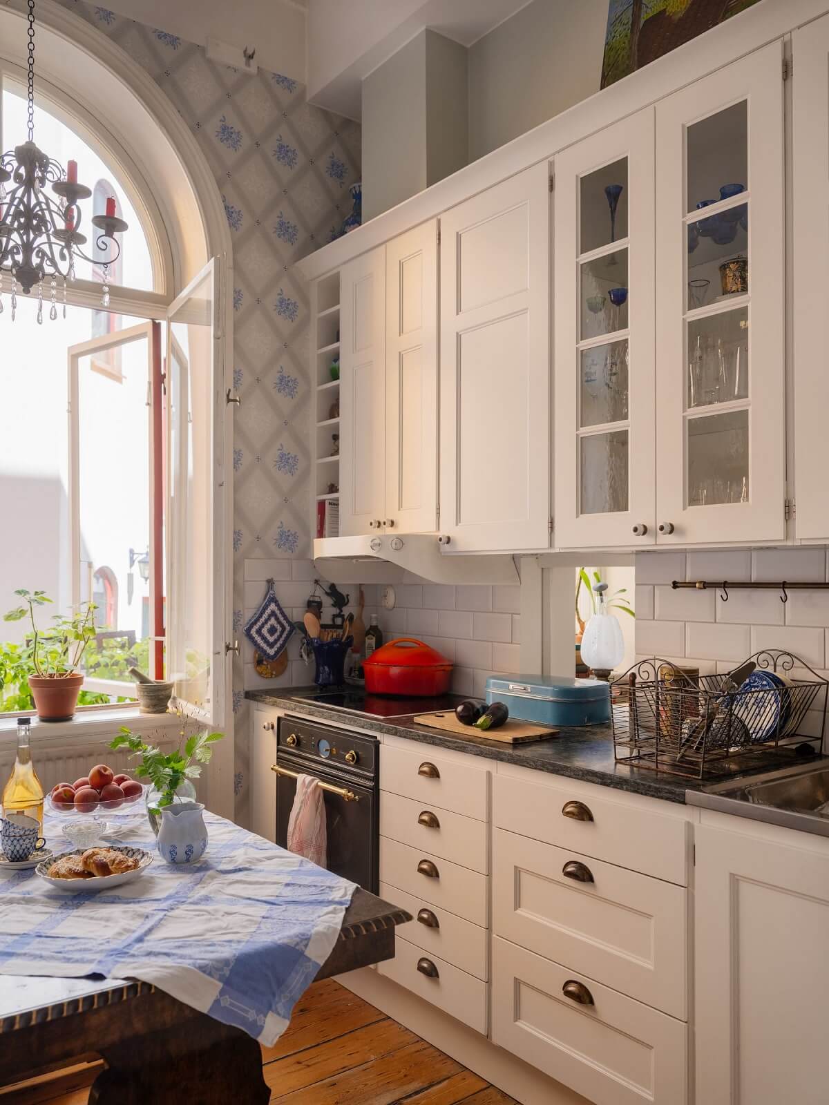 white kitchen with light blue wallpaper and arched window nordroom