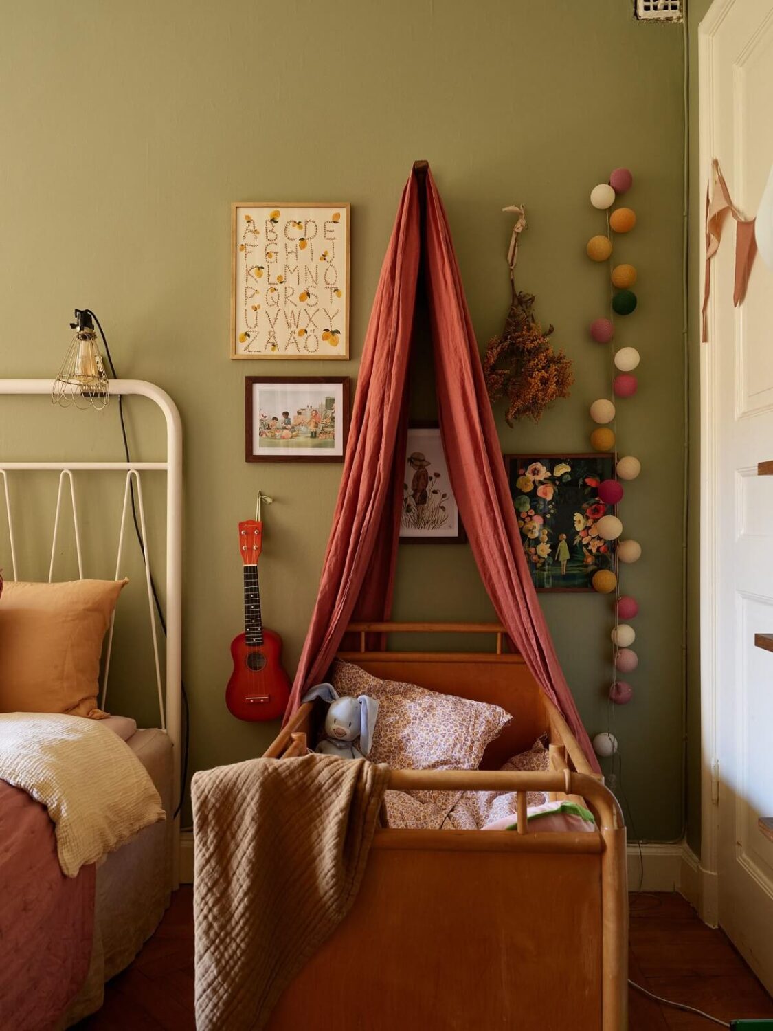 A Cozy 1920s Apartment with Original Details and Wallpaper 24 bedroom with green walls and baby cot with canopy nordroom