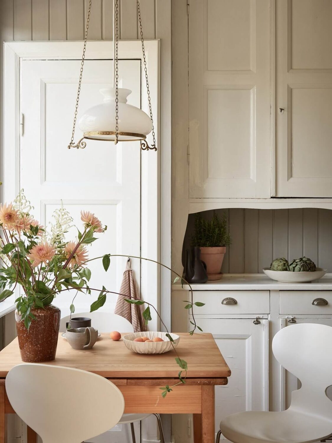 A Light Swedish Apartment with a Charming Kitchen 9 wooden kitchen table original cupboard nordroom