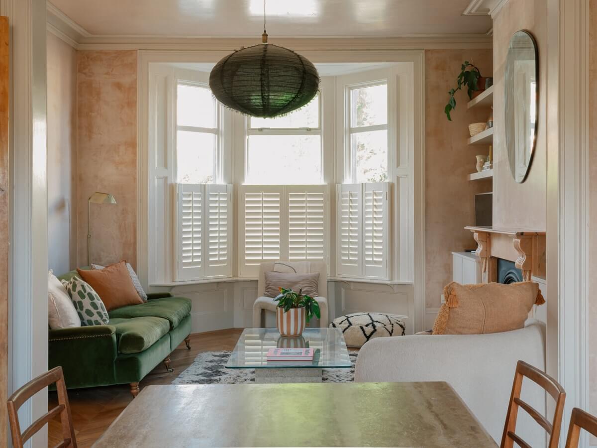 living room bay window plaster pink walls green sofa