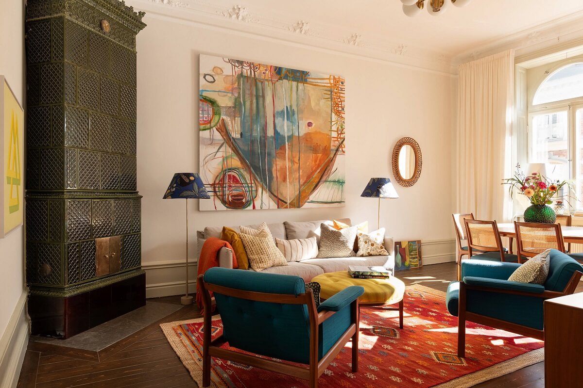 A Beautiful Turn-of-the-Century Apartment with Bold Color Accents 2 living room with green fireplace red rug and blue chairs