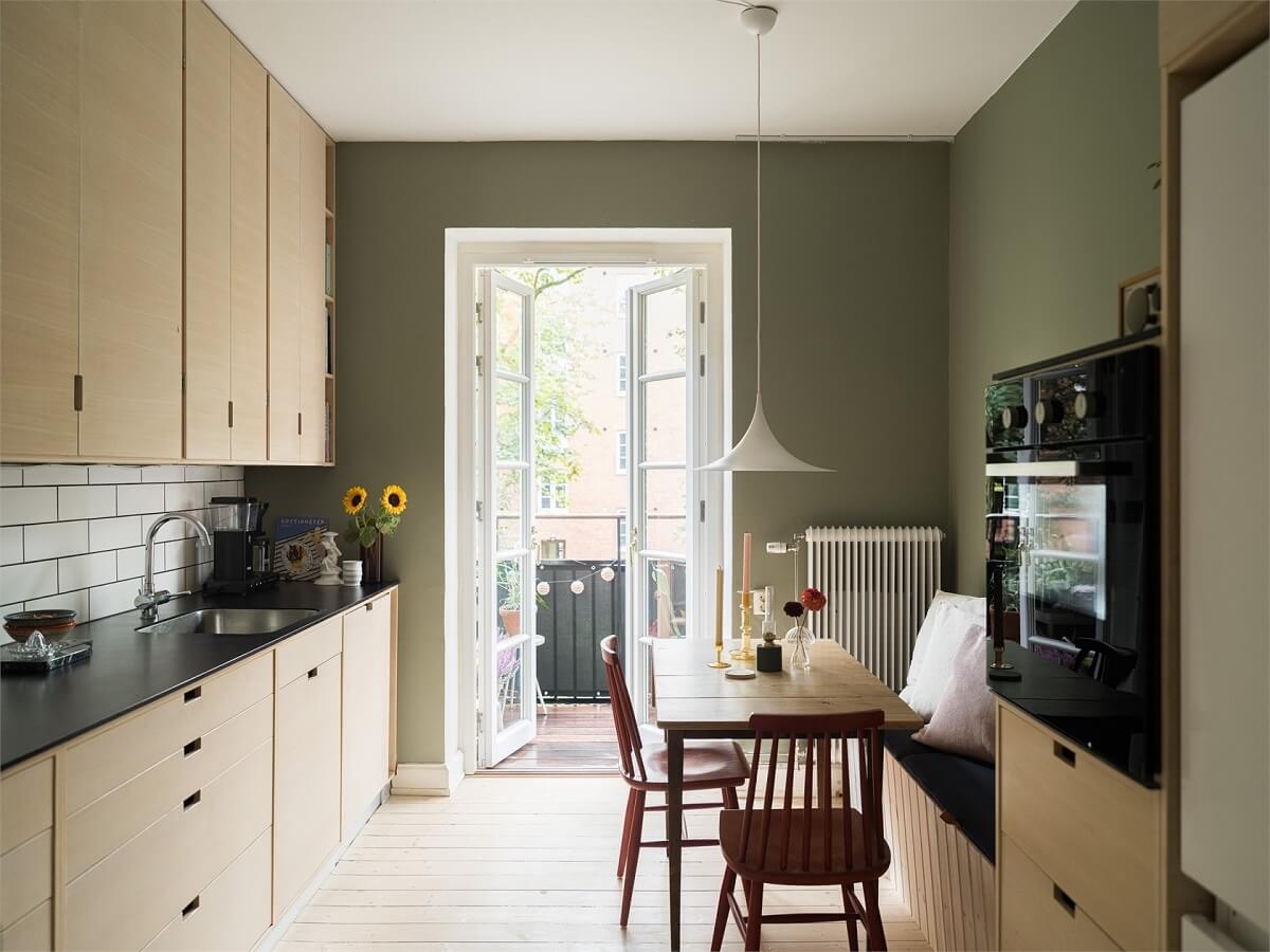 Colorful and Light Rooms in a Swedish One-Bedroom Apartment 8 kitchen with wooden cabinets and sage green walls