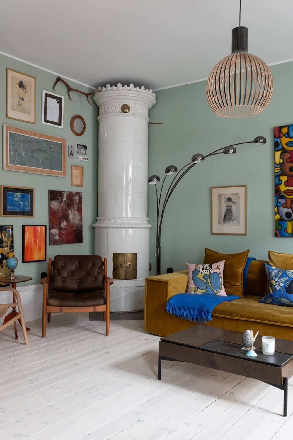 Colorful Art and Furniture in a Stylish Scandi Apartment 3 scandi living room green walls fireplace art and ochre sofa nordroom
