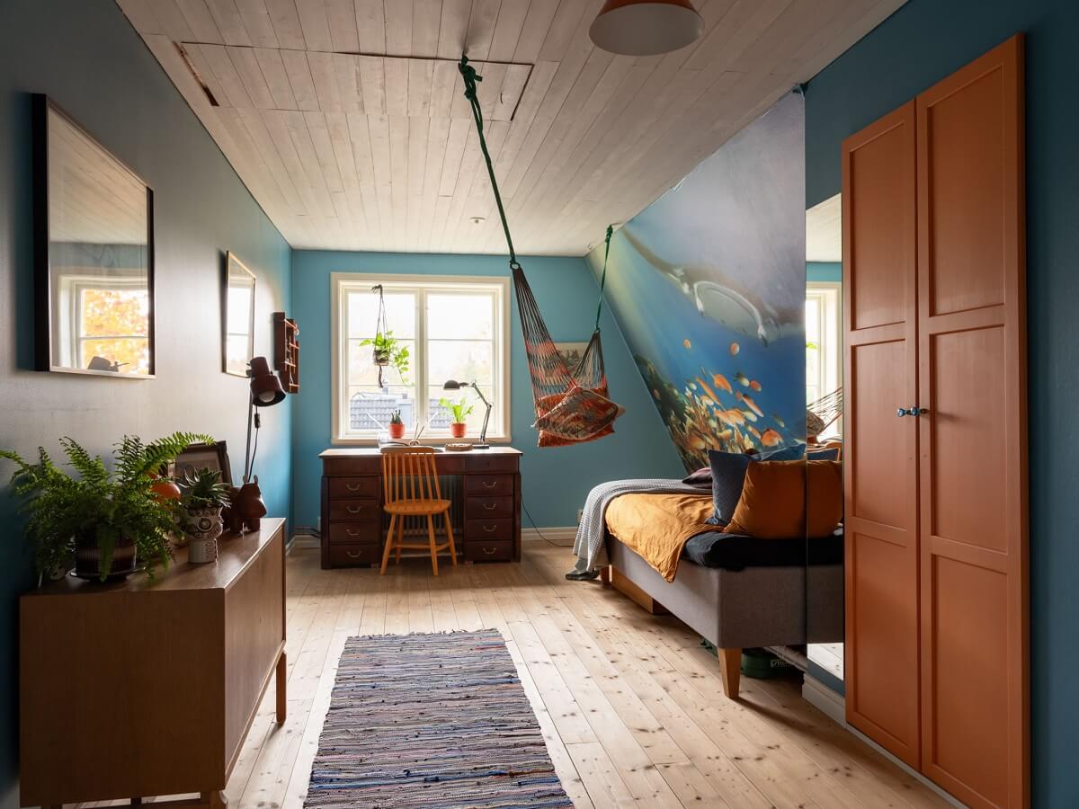 A 1930s Green-Painted Wooden Family Home in Sweden 20 blue bedroom with slanted ceiling built in orange wardrobes and hammock