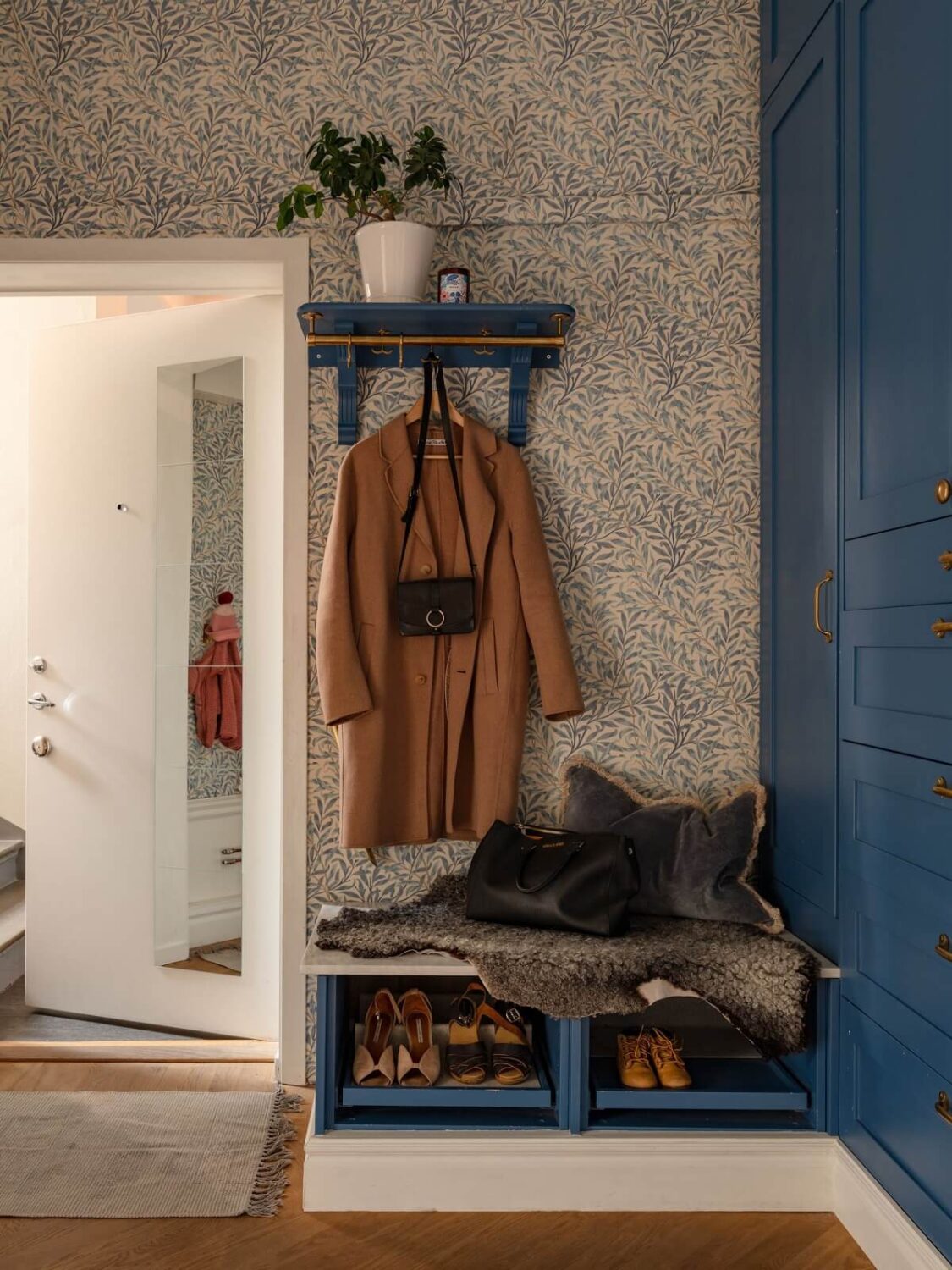 An 1890s Stockholm Apartment with a Blue Bedroom 20 hallway with wallpaper and blue cabinets and shoe storage with bench nordroom