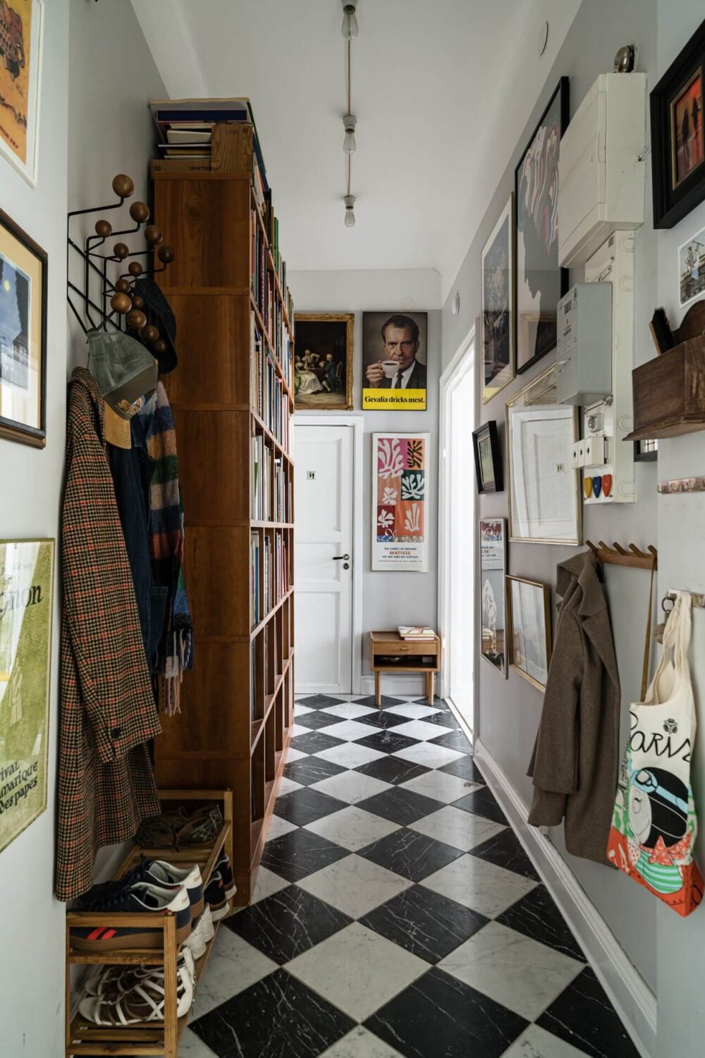 Muted Tones, Art, and Books in a Charming Stockholm Apartment 16 hall with checkerboard marble floor tiles bookcases and art