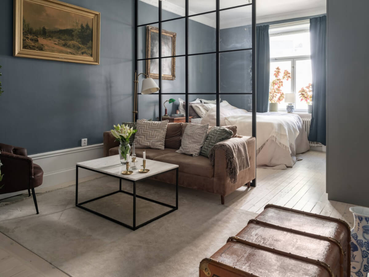 A Classic Studio Apartment with an Industrial Glass Room Divider 1 moody studio apartment with antique art and glass steel room divider nordroom