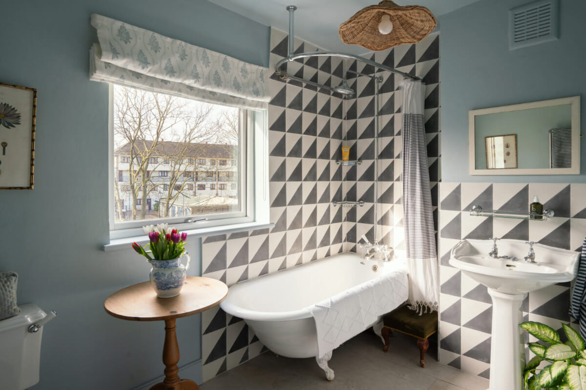A Bright Victorian House with Plaster Walls and Blue Rooms 23 blue bathroom with freestanding bath and black and white geometric tiles