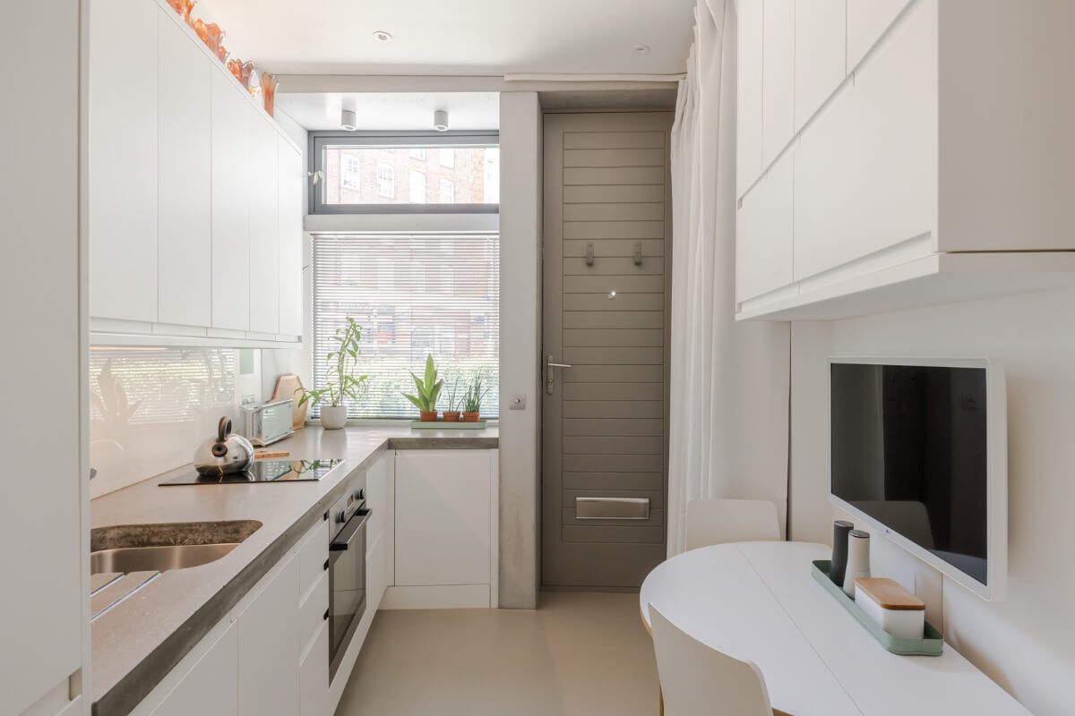 A Narrow Five-Story House with a Roof Garden in London's Clerkenwell 1 white kitchen with front door and curtain hiding coats