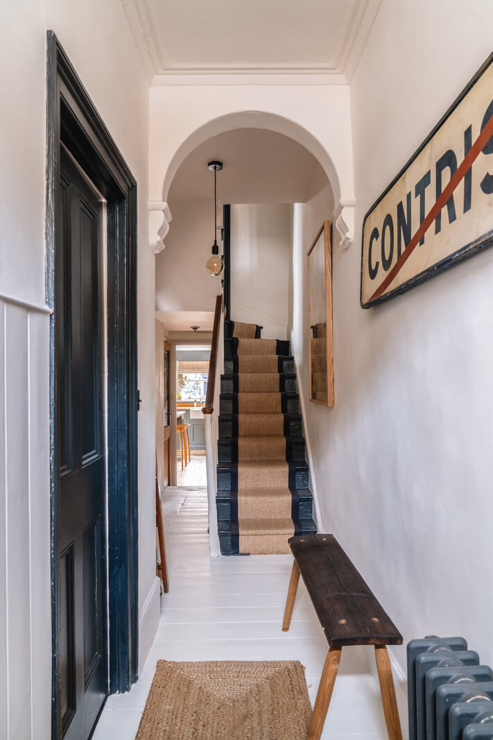 A Cozy Victorian Home Painted in Moody Blue and Gray Tones 9 hall white-painted floorboards arch
