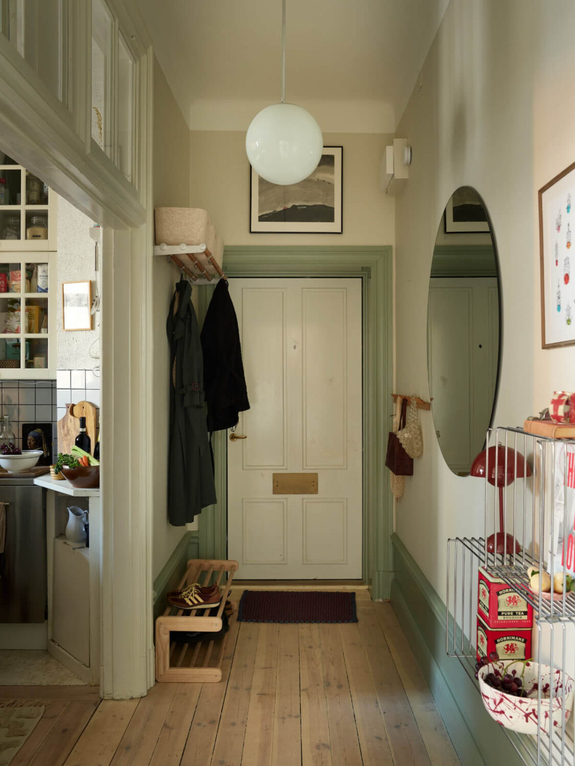 A Muted Color Palette and Smart Storage in a Small Stockholm Apartment 19 hallway large round mirror wooden floorboards