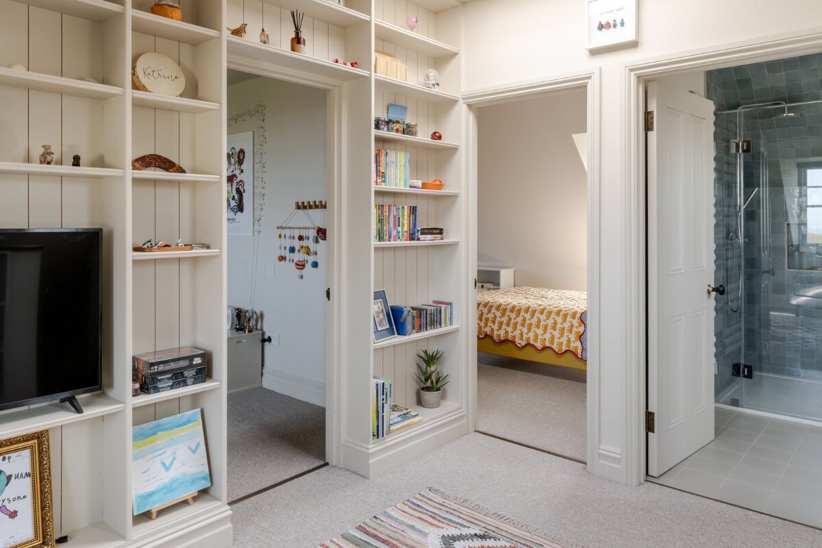 A Grand Edwardian Villa with a Yellow Kitchen and Coastal Views 26 landing with bookshelves and television