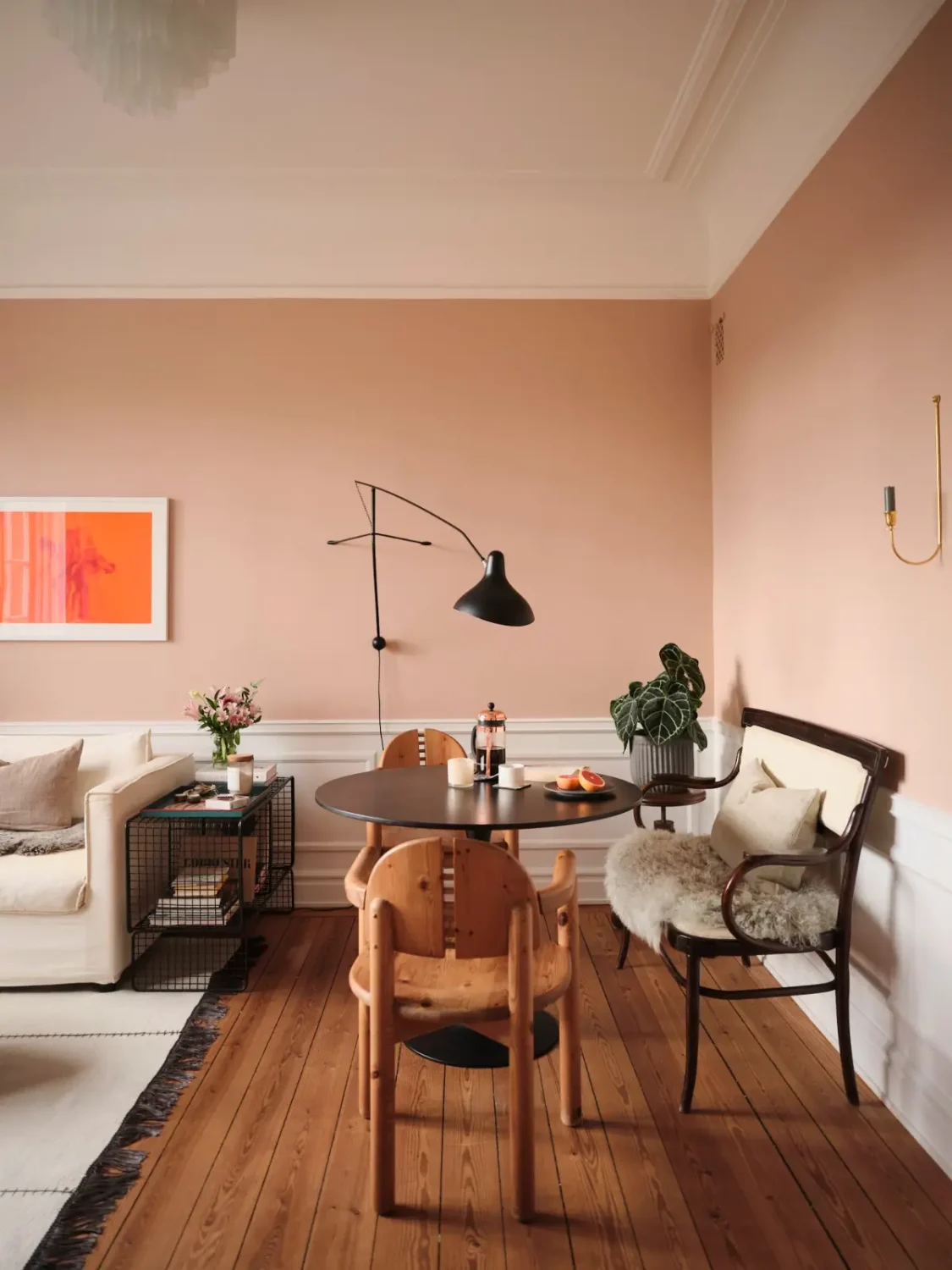 Warm Pink Walls and a Glass Room Divider in a Small Stockholm Apartment 4 living room warm pink walls wooden floorboards black round dining table nordroom